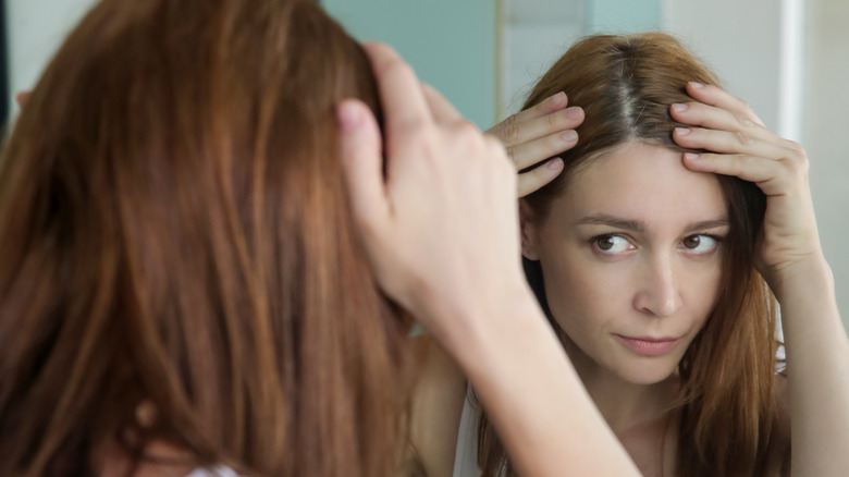 Woman checking her scalp in the mirror