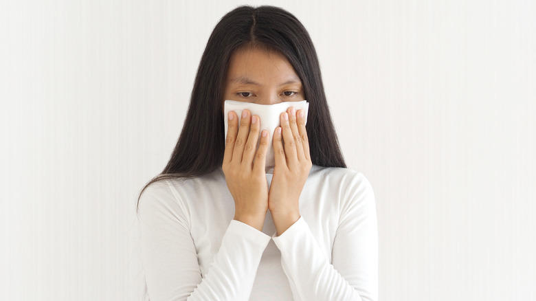 woman blowing nose into tissue