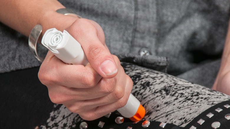 Hand injecting EpiPen in thigh