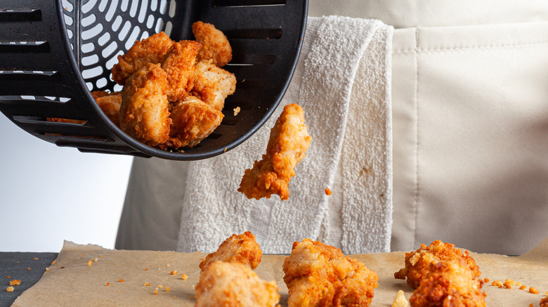 Someone pours chicken nuggets from an air fryer