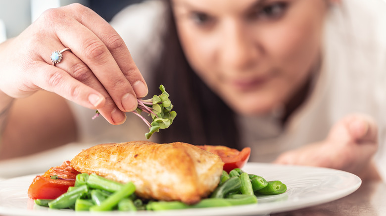 Woman seasoning chicken breast