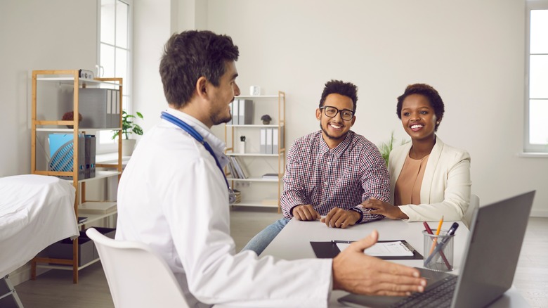 a couple sit smiling in a doctors office 