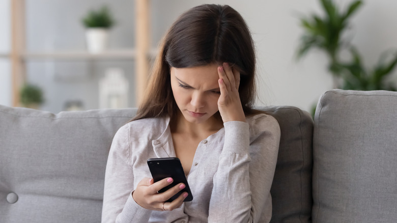woman looking on her phone with upset expression