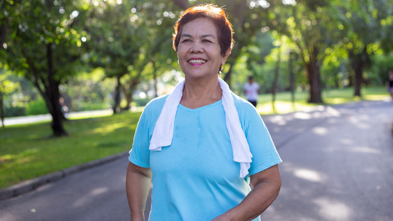 Woman with towel around her shoulders walking through park