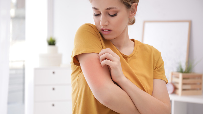 young woman itching her skin as a reaction to her clothing fabric 
