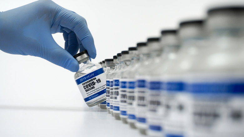gloved hand taking COVID-19 vaccine vial