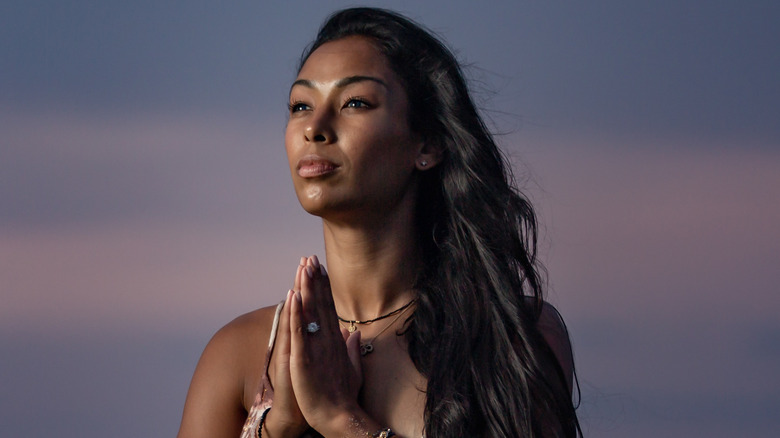 Thara Natalie stands outside with her hands in prayer