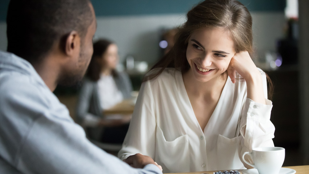 young woman smiling at man sitting across from her