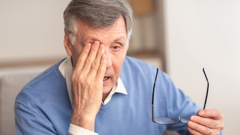 Older man rubbing his eye