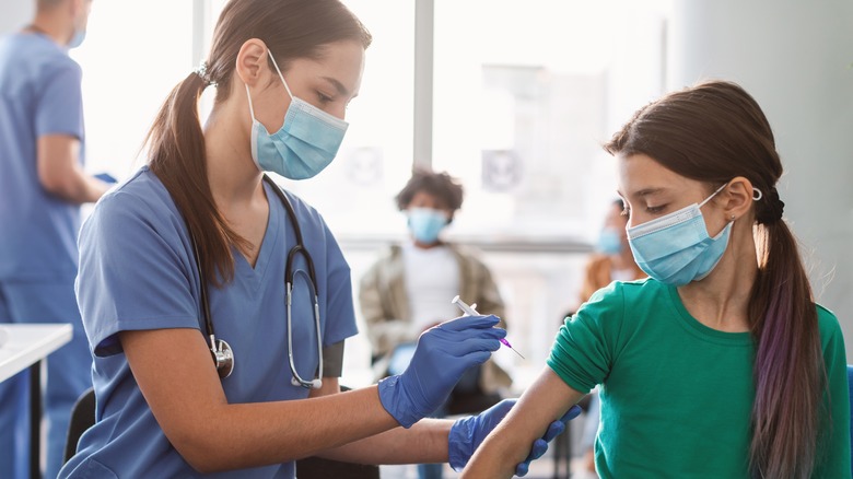 Nurse administering a vaccine to a tween girl.