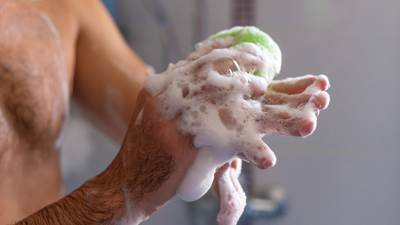 A man taking a bath using a bar of soap
