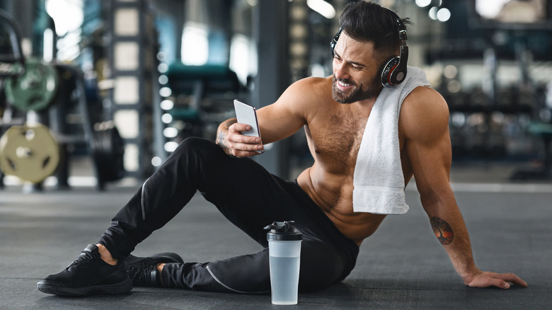 man sitting on gym floor using phone
