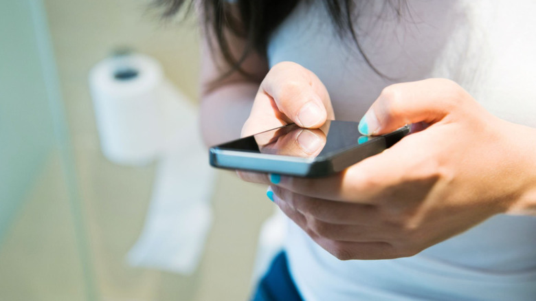 women using her cell phone in the restroom