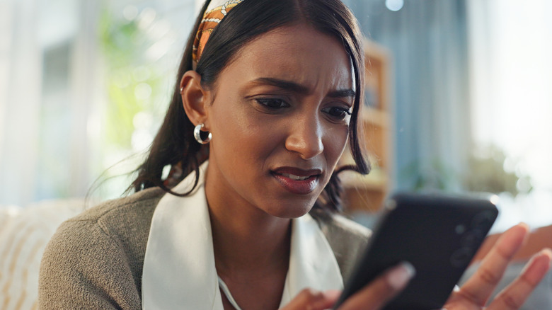 young Gen Z woman surprised by what she is seeing on her phone