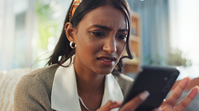 young Gen Z woman surprised by what she is seeing on her phone