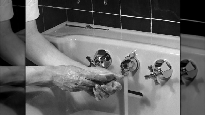 woman washing hands in 1950s sink with bar of soap