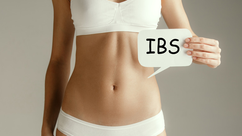 Woman in underwear holding a sign that says "IBS."
