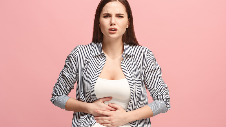 Woman in pain, holding her stomach.