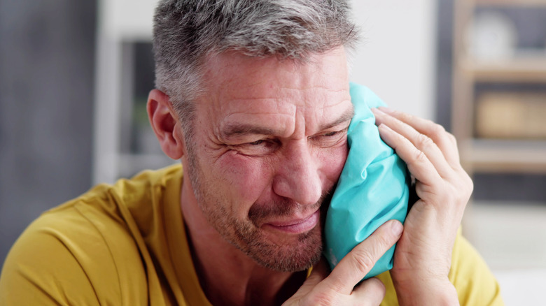 man holding ice pack on face