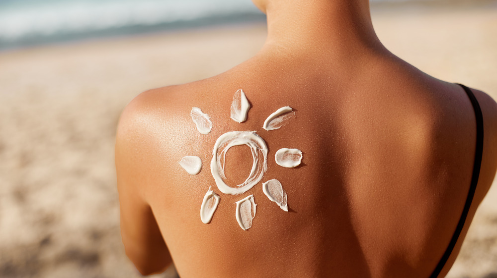 Woman on the beach with the sun drawn in lotion on her back