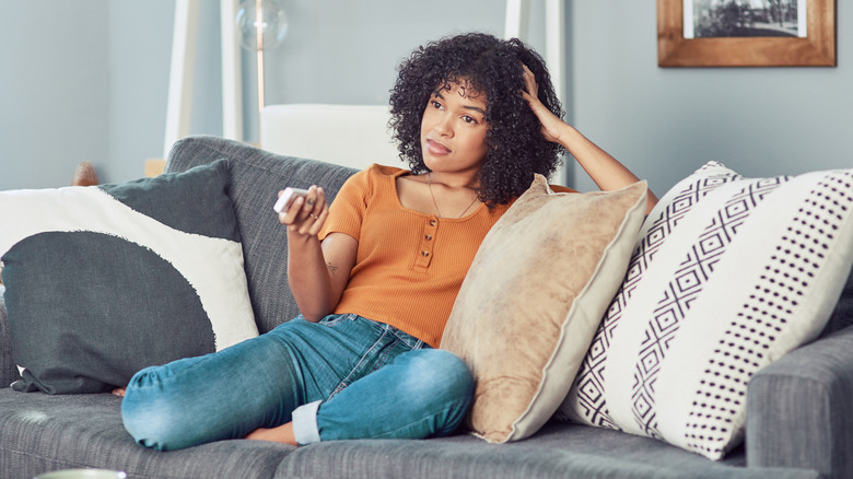 woman watching television on her couch