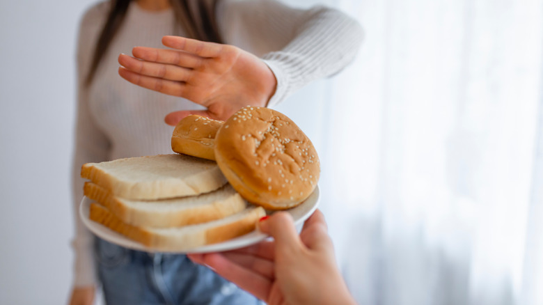 Woman puts her hand out refusing plate of breads