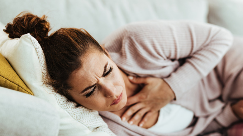 woman lying down holding chest in pain