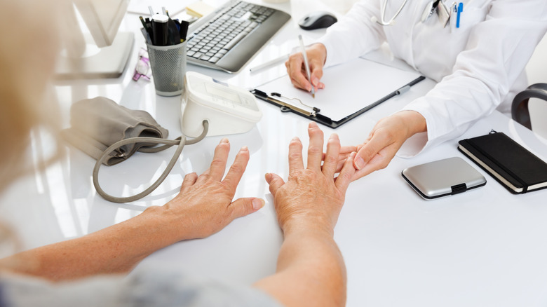 doctor studying older woman's hands