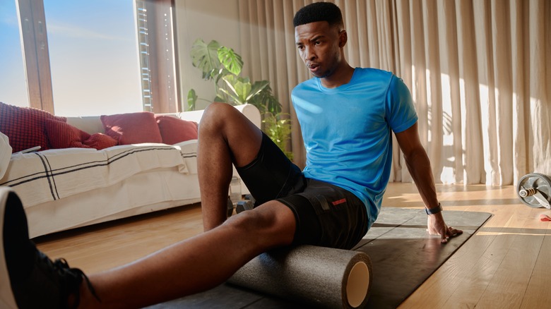 man using foam roller on leg