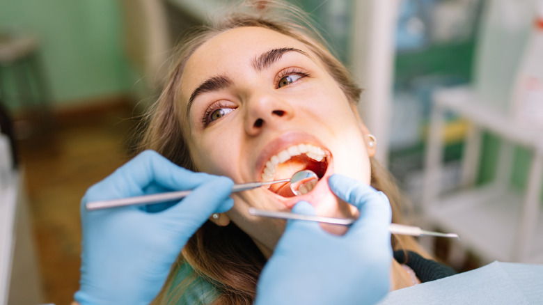 A woman with her mouth open while lying in a dentist chair