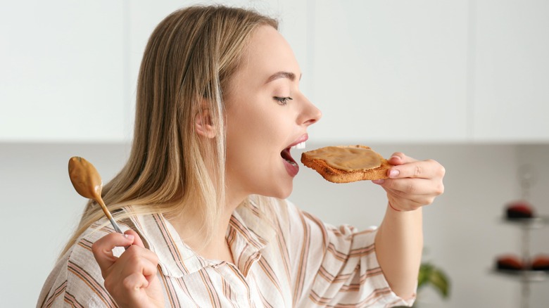 woman eating peanut butter on toast