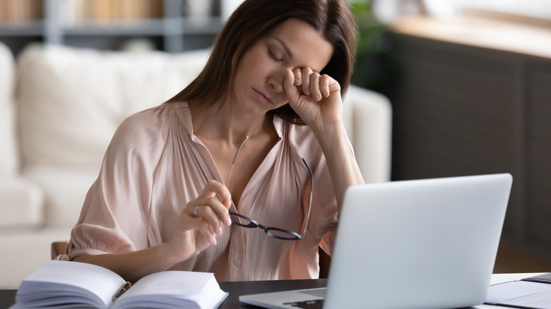 Woman at computer rubbing eyes