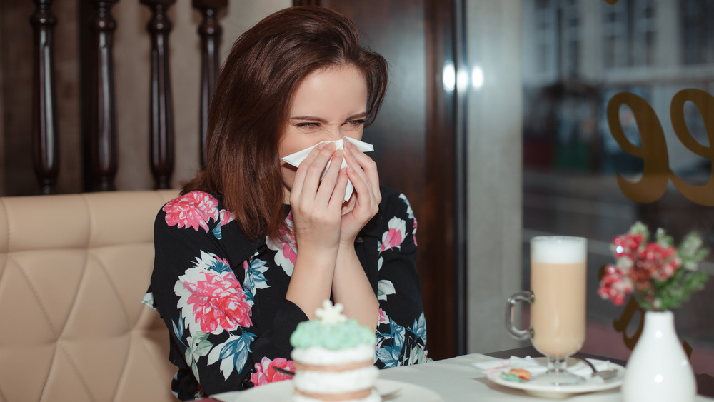 woman blowing nose at table