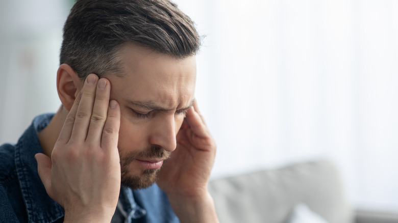 Man with closed eyes rubbing his temples 