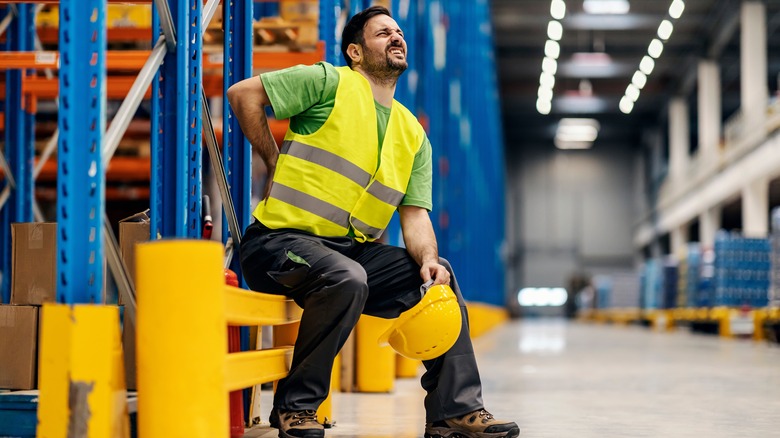 Seated worker rubbing lower back