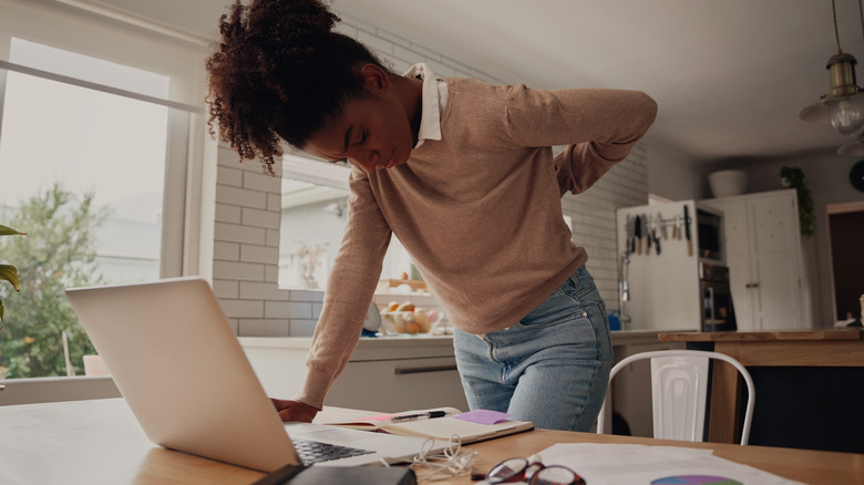 Woman at desk holding back