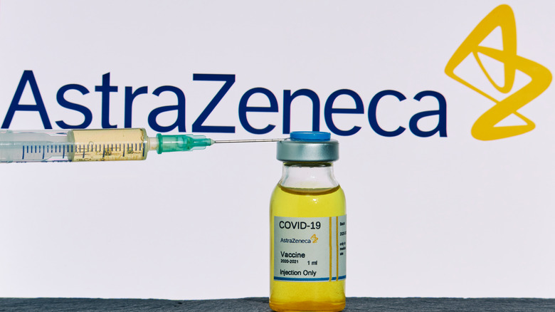 The AstraZeneca logo behind a bottle of vaccine and a syringe