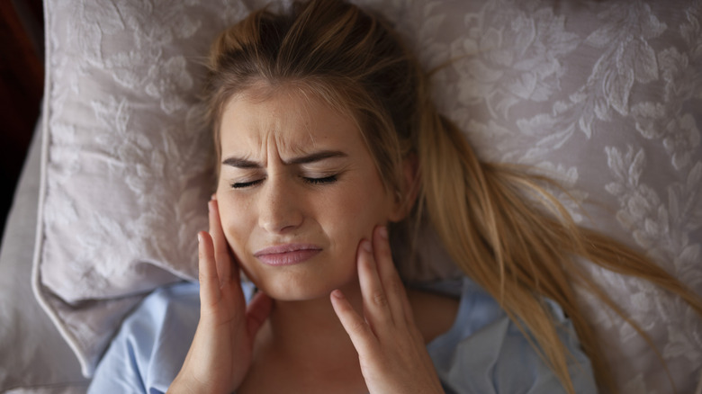 woman waking up with pain from teeth grinding
