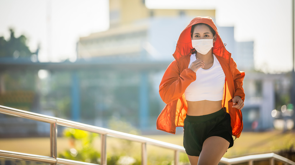 Young woman jogging while wearing a face mask