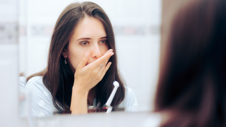 Woman in bathroom with sore mouth