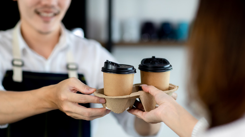 Barista handing tray of coffee cups 