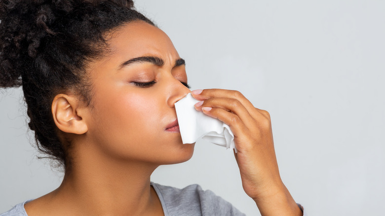 Black woman holding tissue to her nose