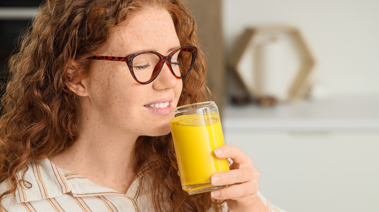 A woman drinking a turmeric-based drink