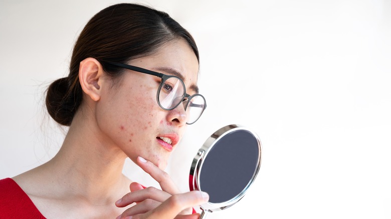 woman examining her face in a mirror