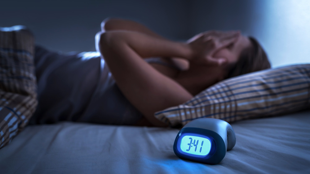 Woman in bed with hands on face