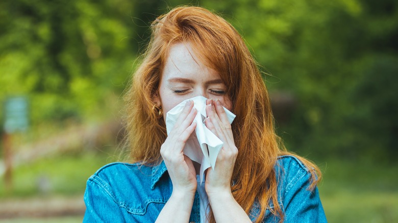 Woman outdoors blowing her nose