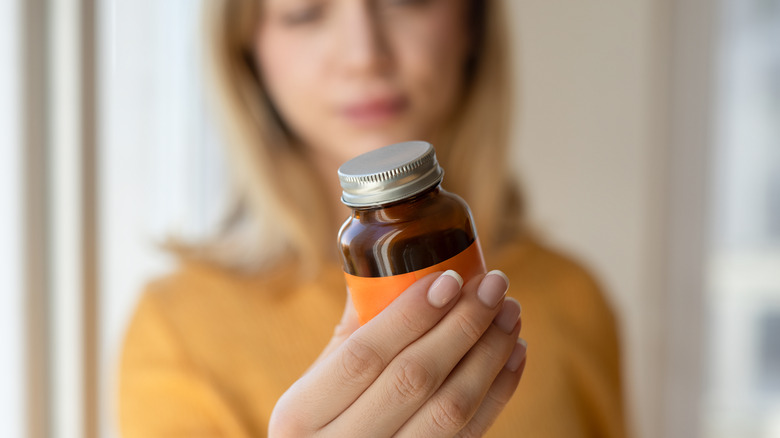 young woman holding a bottle of vitamins or minerals