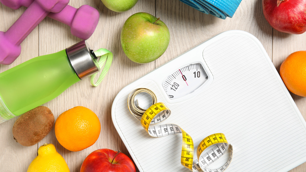 A scale next to fruits and exercise-related items