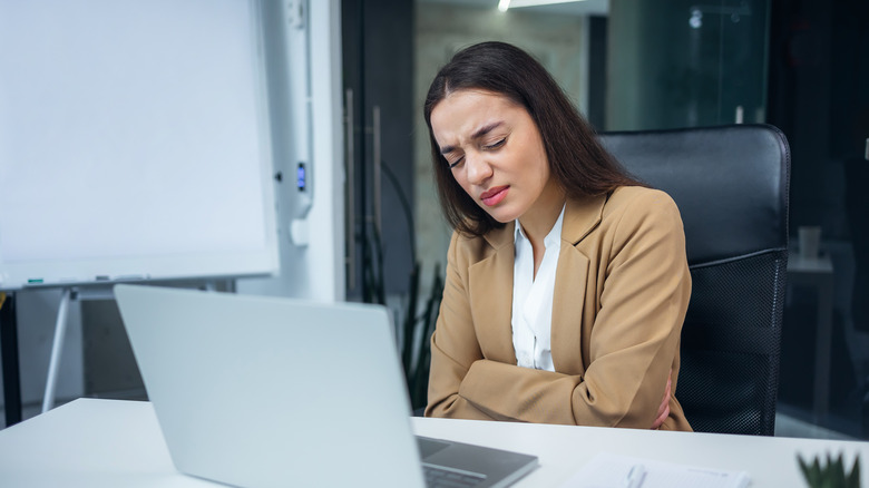 woman with gastritis pain sitting at laptop