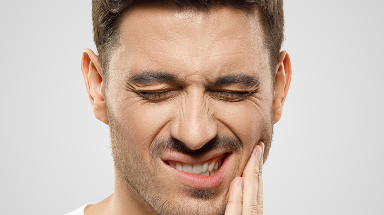 man holding jaw in discomfort